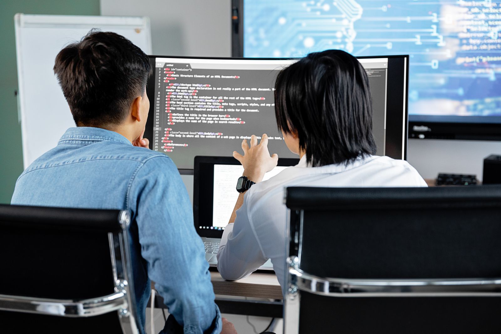 Software professionals collaborating on code and web systems in a modern office